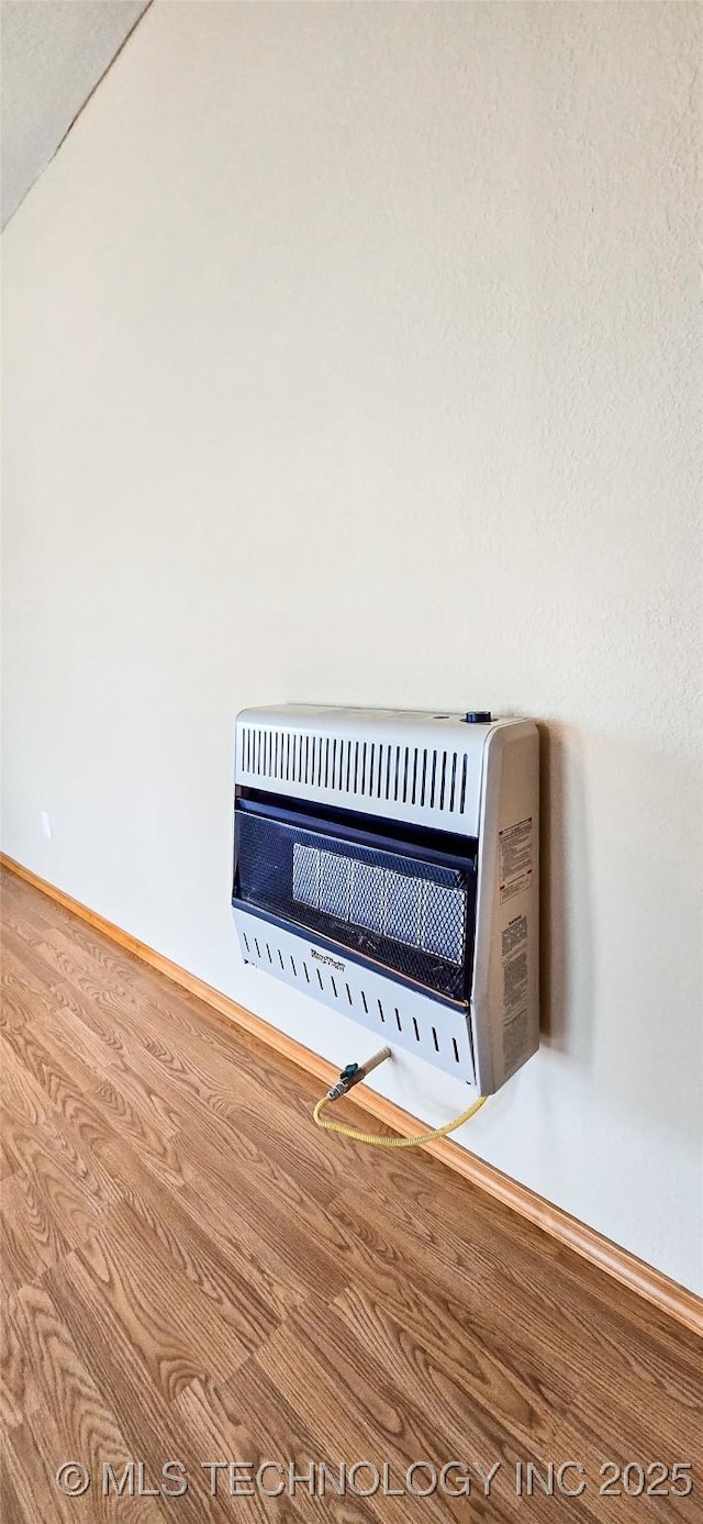 interior details featuring baseboards, heating unit, and wood finished floors