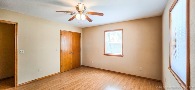 unfurnished bedroom featuring a closet, ceiling fan, light wood-type flooring, and baseboards