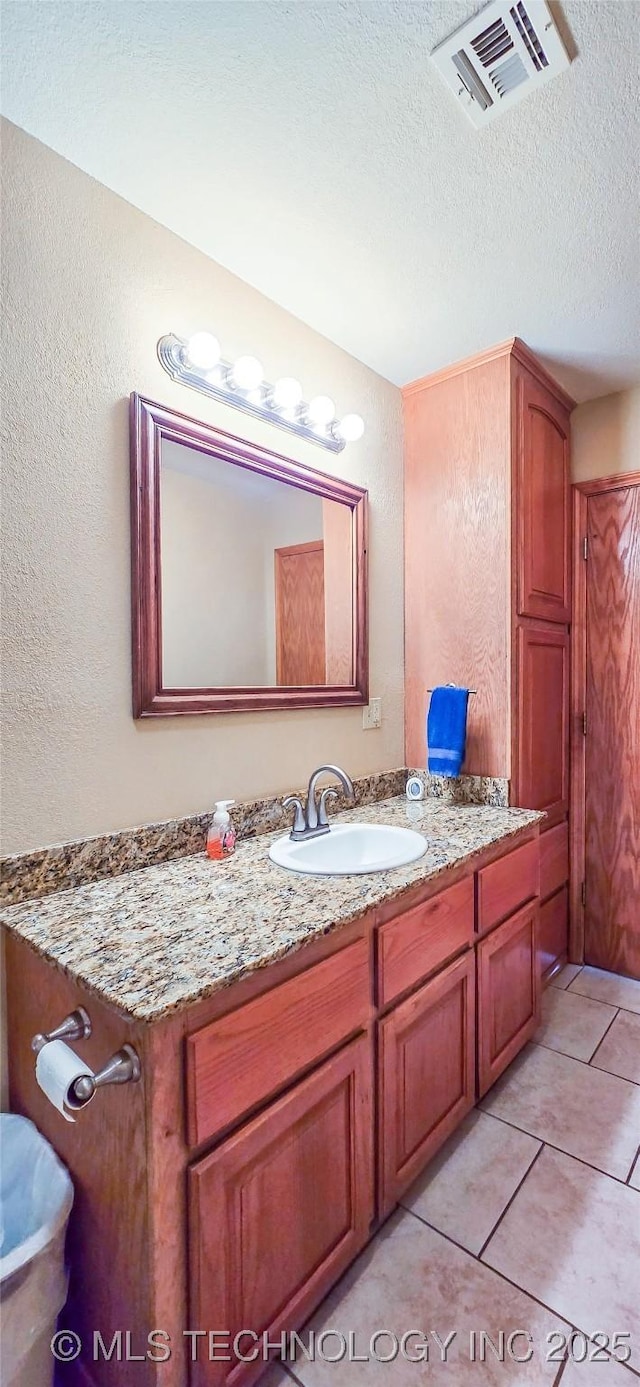bathroom with tile patterned floors, visible vents, a textured ceiling, and vanity