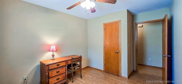 office area with baseboards, light wood-type flooring, and ceiling fan