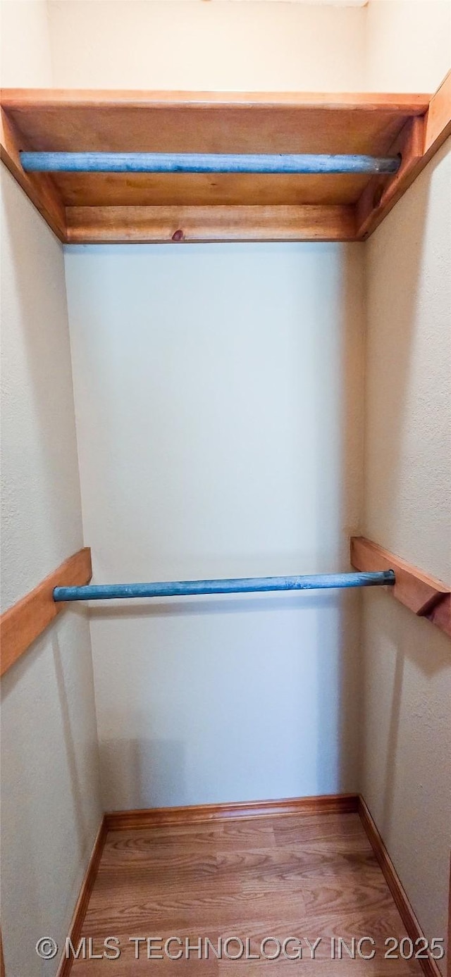 walk in closet with wood finished floors