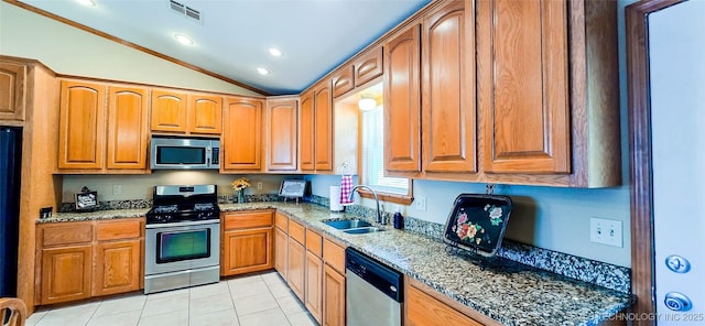 kitchen with stone counters, lofted ceiling, a sink, appliances with stainless steel finishes, and brown cabinets