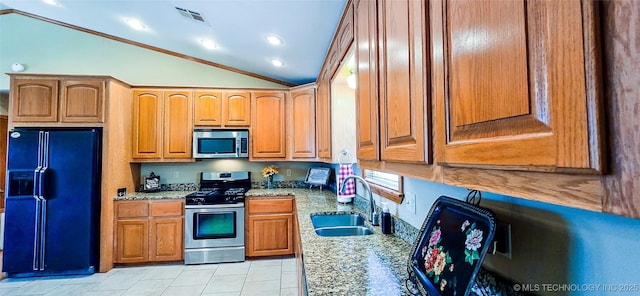 kitchen featuring light stone counters, visible vents, lofted ceiling, a sink, and appliances with stainless steel finishes