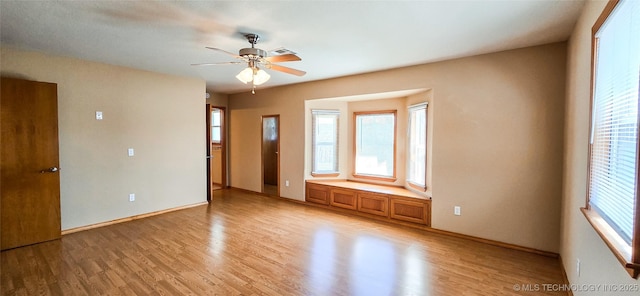 spare room with light wood-style floors, a healthy amount of sunlight, and ceiling fan