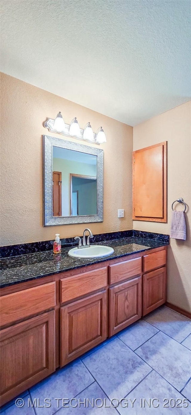 bathroom with tile patterned flooring, a textured ceiling, and vanity