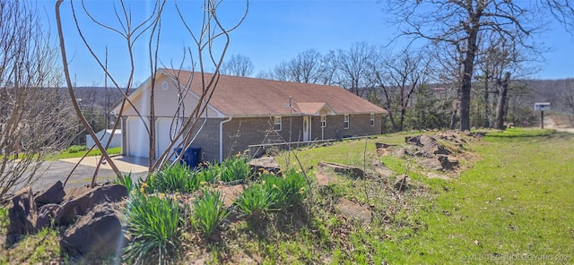 rear view of house featuring brick siding, concrete driveway, an attached garage, and a lawn