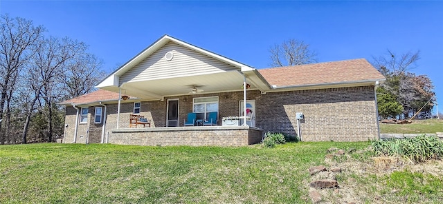 back of house with a patio area, a lawn, brick siding, and roof with shingles