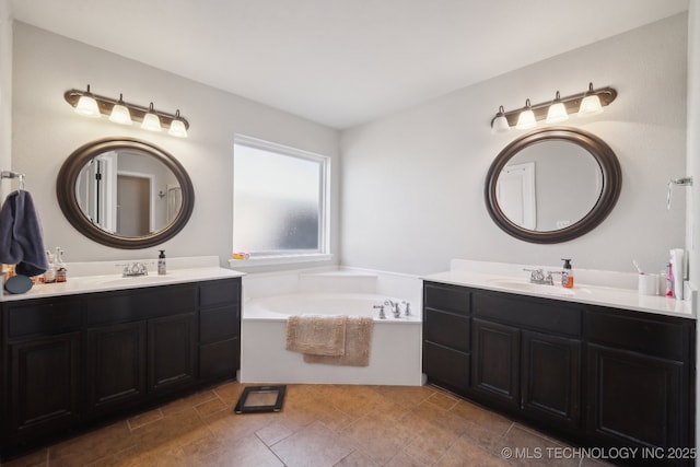 bathroom featuring two vanities, a bath, and a sink