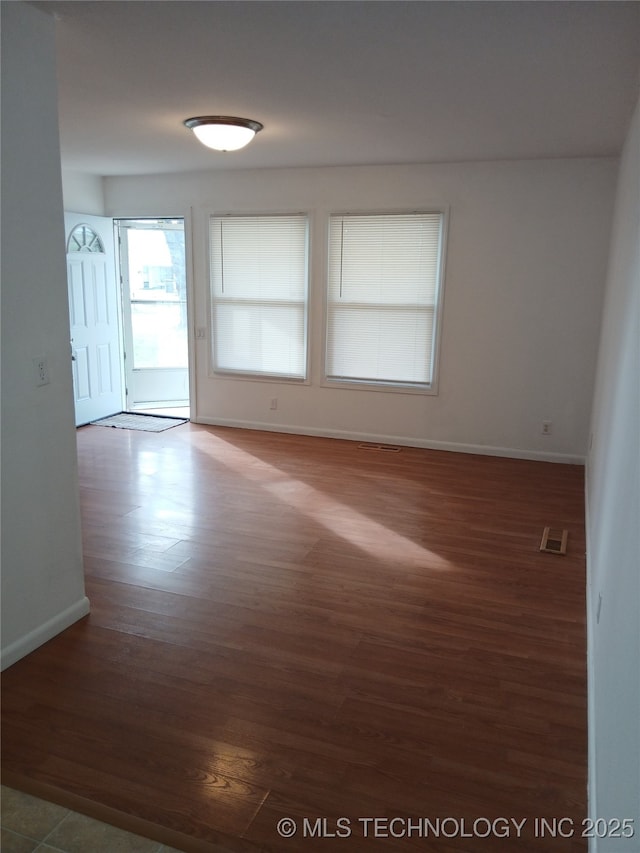 unfurnished room with baseboards, visible vents, and wood finished floors