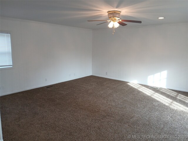 spare room with ceiling fan, visible vents, ornamental molding, and dark colored carpet