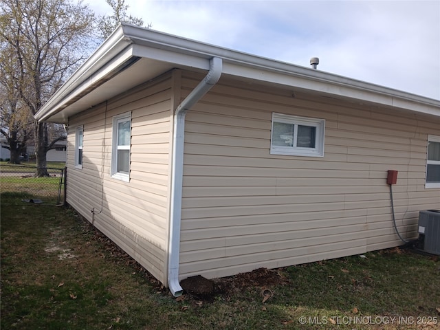 view of property exterior featuring central air condition unit, fence, and a yard