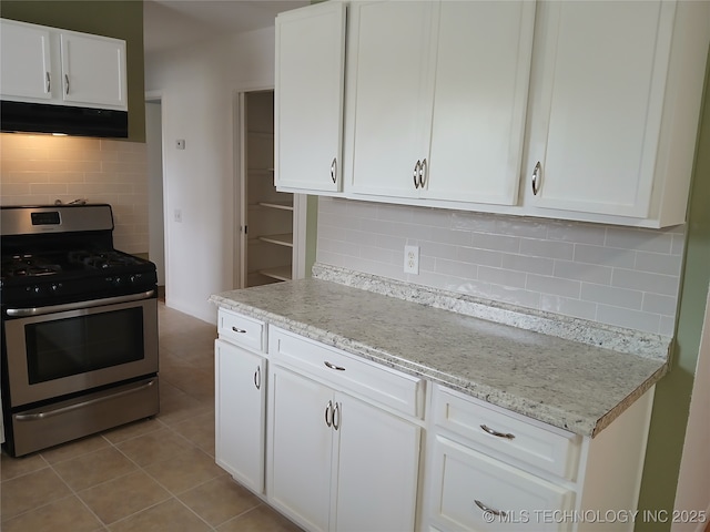 kitchen featuring white cabinets, light tile patterned flooring, under cabinet range hood, and gas stove