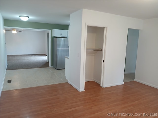interior space with baseboards, visible vents, light wood-style floors, and freestanding refrigerator