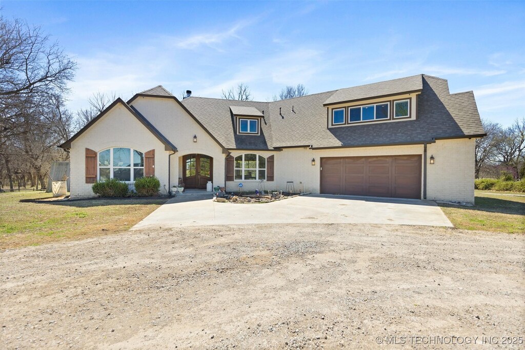 1392 E 171st St, Skiatook, OK 74070 - view of front of house featuring a garage, brick siding, concrete driveway, and a shingled roof