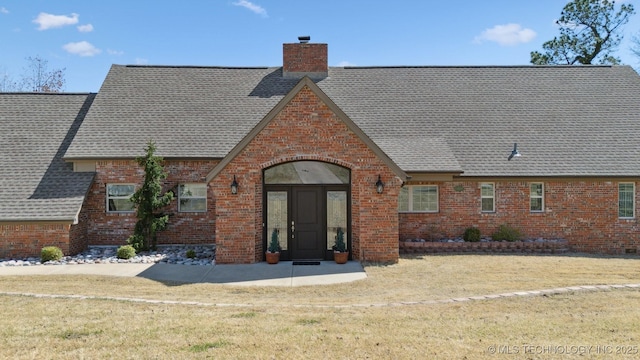 122 Osage Ridge Dr, Sand Springs, OK 74063 - back of house featuring brick siding, a chimney, a yard, and a shingled roof
