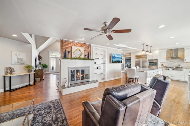 122 Osage Ridge Dr, Sand Springs, OK 74063 - living area with light wood-style flooring, a brick fireplace, baseboards, and ceiling fan