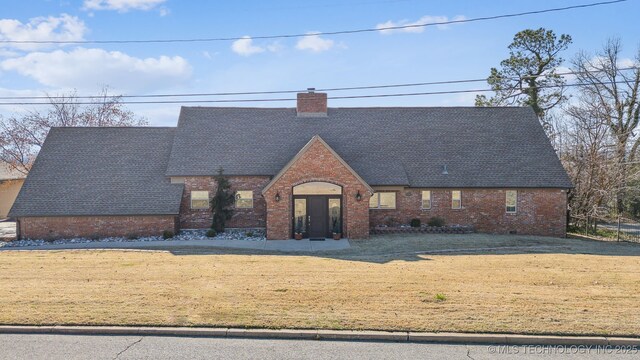 122 Osage Ridge Dr, Sand Springs, OK 74063 - tudor home with brick siding, a chimney, a shingled roof, and a front lawn