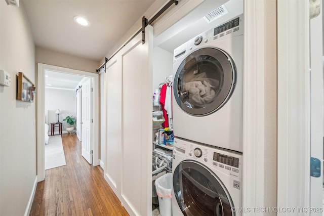 122 Osage Ridge Dr, Sand Springs, OK 74063 - laundry room featuring baseboards, a barn door, laundry area, stacked washer and clothes dryer, and wood finished floors