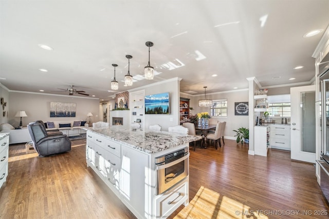 122 Osage Ridge Dr, Sand Springs, OK 74063 - kitchen featuring wood finished floors, oven, hanging light fixtures, ceiling fan with notable chandelier, and open floor plan