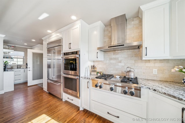 122 Osage Ridge Dr, Sand Springs, OK 74063 - kitchen featuring stainless steel appliances, white cabinetry, wall chimney exhaust hood, and light wood-style flooring