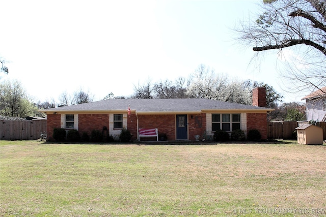 ranch-style home featuring an outdoor structure, a storage shed, fence, and a front lawn