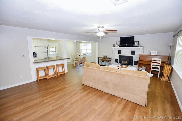 1004 S Owens Ave, Tahlequah, OK 74464 - living room featuring wood finished floors, a ceiling fan, baseboards, and a brick fireplace
