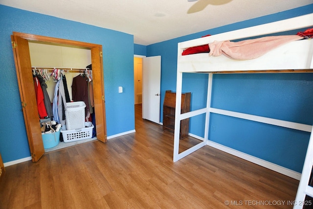 1004 S Owens Ave, Tahlequah, OK 74464 - unfurnished bedroom with wood finished floors, a closet, baseboards, and a ceiling fan