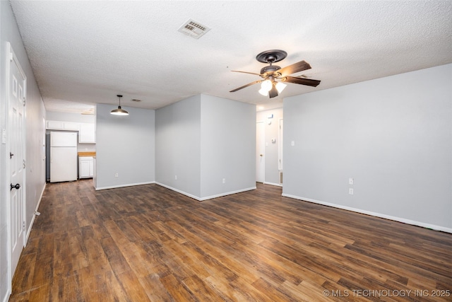 unfurnished living room with visible vents, dark wood-type flooring, baseboards, ceiling fan, and a textured ceiling
