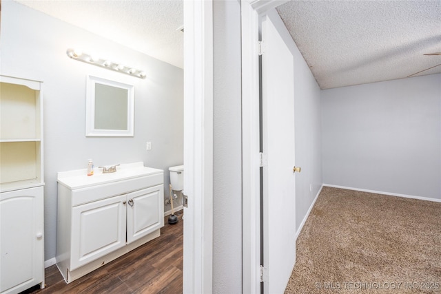 bathroom with baseboards, a textured ceiling, wood finished floors, and vanity