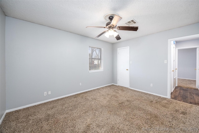 unfurnished room with visible vents, a textured ceiling, carpet floors, baseboards, and ceiling fan