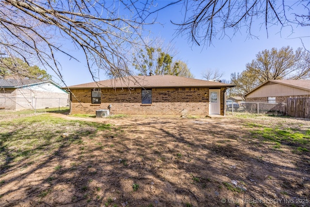 rear view of house featuring central air condition unit, brick siding, and fence