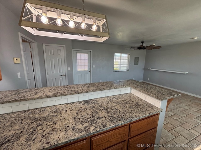 34 S Mount Calvary Rd, Hendrix, OK 74741 - kitchen featuring a ceiling fan, brown cabinets, baseboards, decorative light fixtures, and light stone countertops