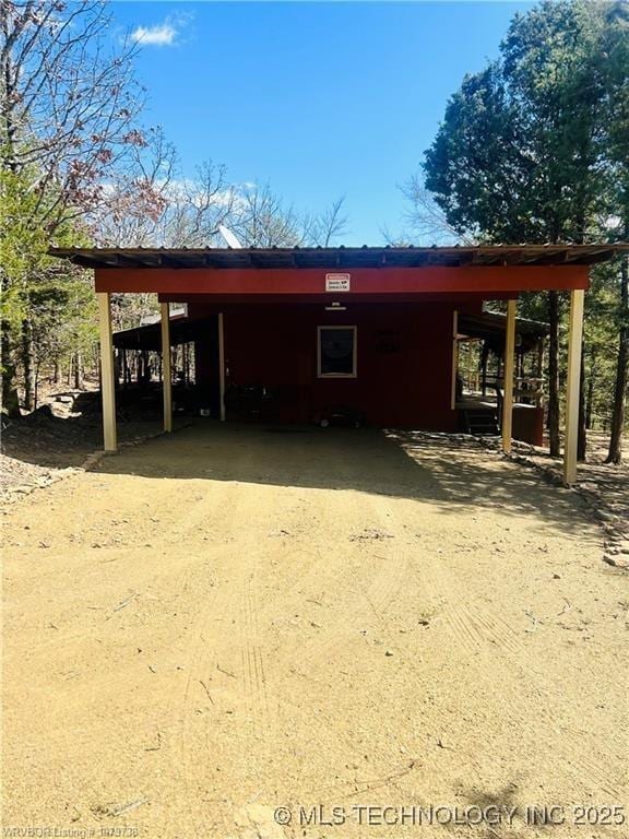 view of outdoor structure featuring an attached carport and concrete driveway