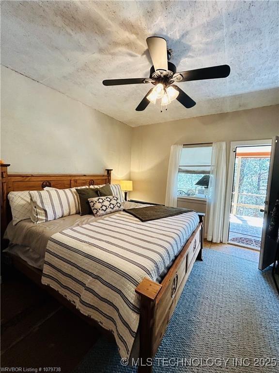 carpeted bedroom featuring access to exterior, a ceiling fan, and a textured ceiling