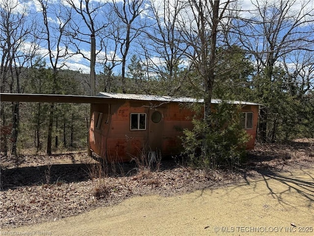 view of home's exterior featuring a forest view, metal roof, and a carport
