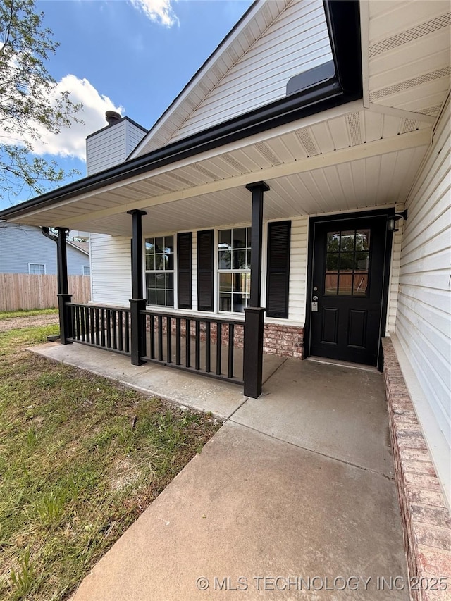 1103 S Chickasaw Pl, Claremore, OK 74017 - view of exterior entry with a porch, brick siding, fence, and a chimney