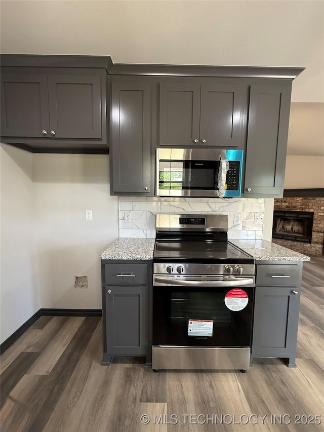 1103 S Chickasaw Pl, Claremore, OK 74017 - kitchen featuring stainless steel appliances, light stone counters, gray cabinets, and light wood-style floors