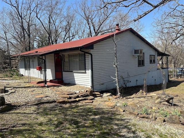view of home's exterior featuring crawl space, a chimney, and metal roof