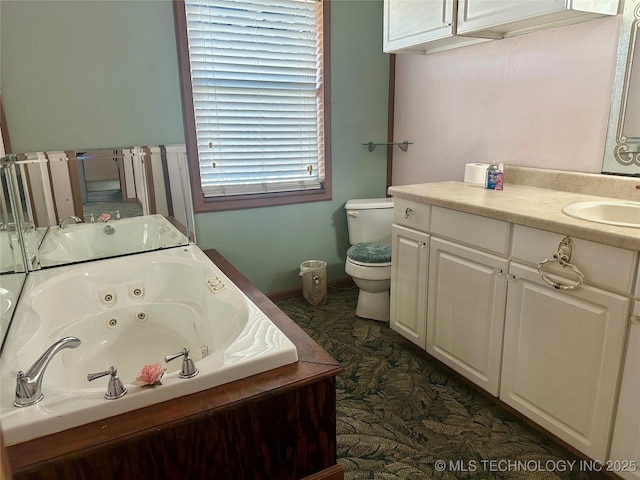 bathroom featuring vanity, a jetted tub, and toilet