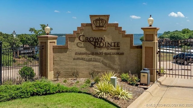 community / neighborhood sign with a gate and fence