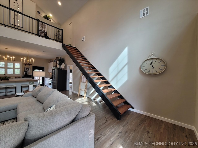 117700 S 4214th Rd, Eufaula, OK 74432 - living area with stairs, a chandelier, a high ceiling, baseboards, and wood finished floors