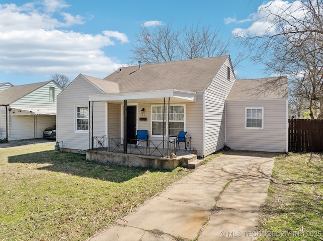 bungalow with a shingled roof, fence, a porch, a front yard, and driveway
