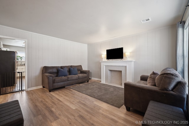 living room with visible vents, a fireplace with flush hearth, and light wood finished floors