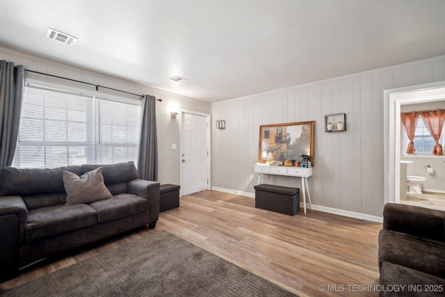 living area featuring light wood-type flooring, visible vents, and baseboards