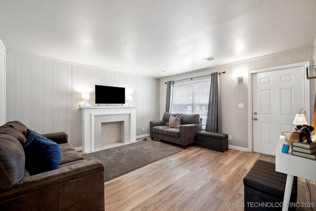 living room with visible vents, baseboards, light wood-style flooring, and a fireplace