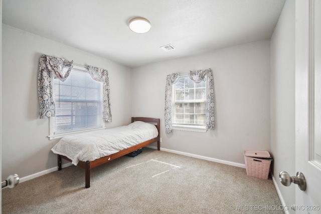 carpeted bedroom with visible vents, multiple windows, and baseboards