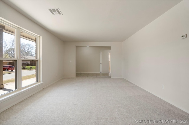 spare room featuring light colored carpet, visible vents, and baseboards