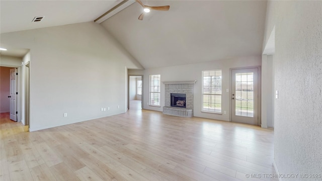 11762 N 156th E Ave, Collinsville, OK 74021 - unfurnished living room featuring a ceiling fan, beamed ceiling, high vaulted ceiling, a fireplace, and light wood-style flooring