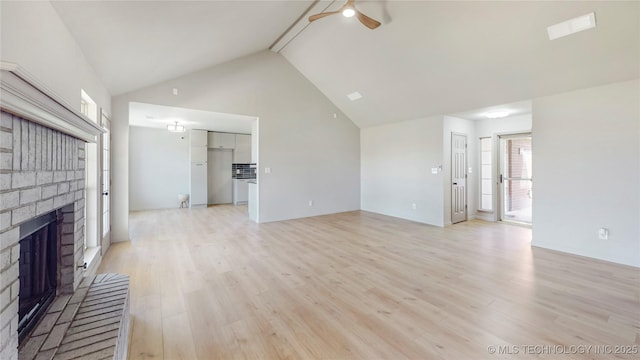 unfurnished living room with high vaulted ceiling, light wood finished floors, visible vents, a ceiling fan, and a fireplace