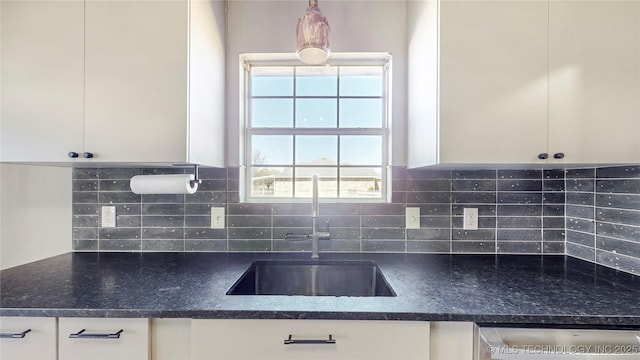kitchen featuring white cabinets, a sink, stainless steel dishwasher, and tasteful backsplash